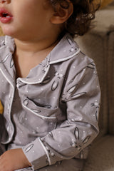 Child wearing a gray pajama set with animal prints on a soft background