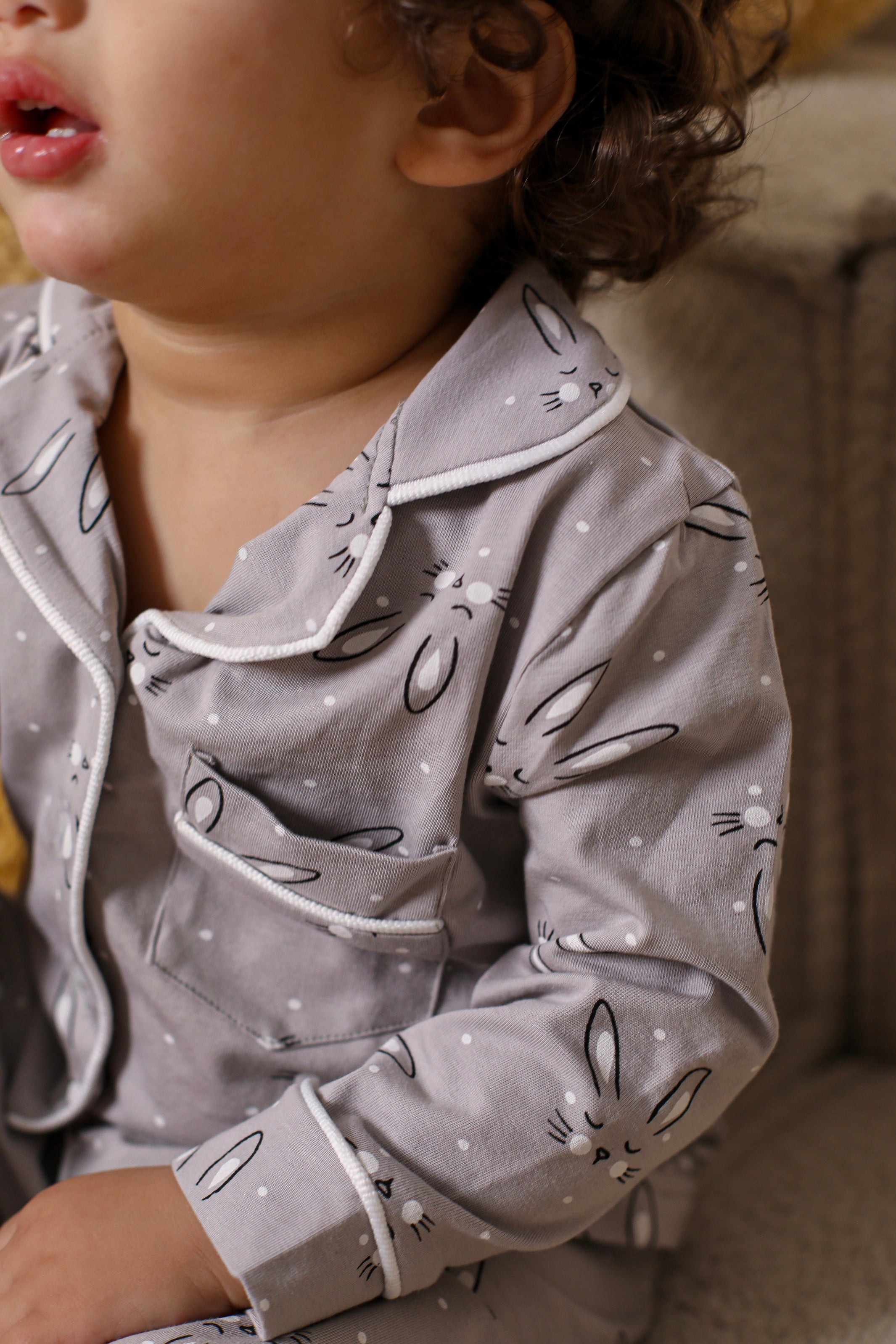 Child wearing a gray pajama set with animal prints on a soft background