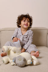 Child in pajamas sitting on a couch with a large teddy bear