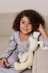 Child in pajamas holding a plush toy on a couch